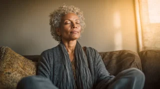Person sitting in a relaxed open posture with hands loose in their lap, expression showing quiet calm and release